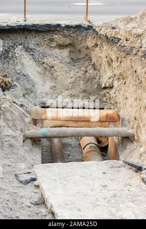 Rostige Kanalisationsrohre - Unterirdisch. Reparatur der Erdwasserversorgung, vertikales Foto. Stockfoto