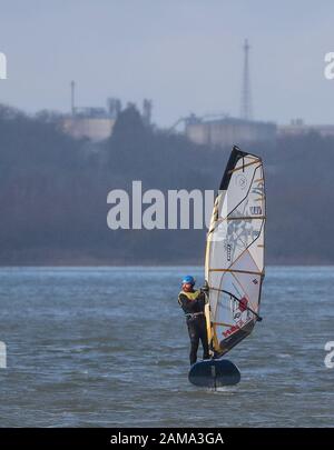 Fawley, Hampshire, Großbritannien. Januar 2020. Wetter in Großbritannien: Ein Windsurfer macht das Beste aus den windigen Bedingungen mit Böen bis zu 28 mph, wenn er die Fawley Power Station passiert. Kredit: Stuart Martin/Alamy Live News Stockfoto