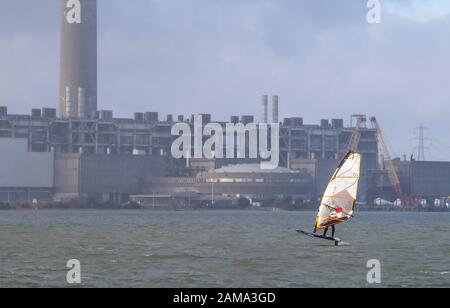 Fawley, Hampshire, Großbritannien. Januar 2020. Wetter in Großbritannien: Ein Windsurfer macht das Beste aus den windigen Bedingungen mit Böen bis zu 28 mph, wenn er die Fawley Power Station passiert. Kredit: Stuart Martin/Alamy Live News Stockfoto