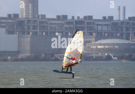 Fawley, Hampshire, Großbritannien. Januar 2020. Wetter in Großbritannien: Ein Windsurfer macht das Beste aus den windigen Bedingungen mit Böen bis zu 28 mph, wenn er die Fawley Power Station passiert. Kredit: Stuart Martin/Alamy Live News Stockfoto