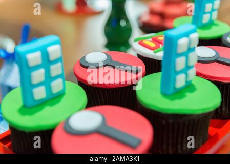 Personalisierbare Cupcakes mit Lupenfondant, Ferngläsern, Fußabdrücken und anderen konzeptuellen Forschungsformen auf einem schwarzen Tablett Kinder-Party-Cak Stockfoto