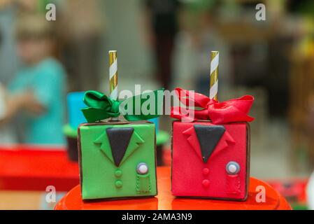 Personalisierte Süßigkeiten im grünen und roten Mantelformat in Fondant. Bunte Zahnstocher mit Satin-Schleifen. Kinderparty Kuchen Tischdekoration. Selektiv Stockfoto