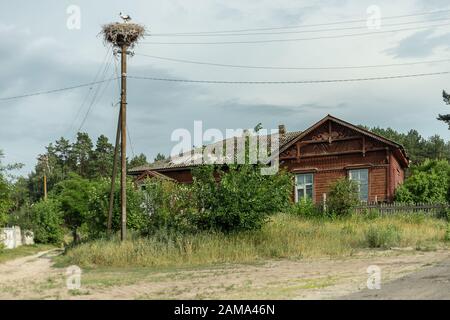 Altes Haus und ein Storchennest auf einer Säule Stockfoto