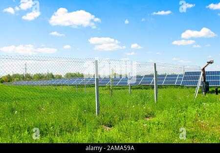 Solaranlage aus vielen großen Modulen (Photovoltaik-Solarpaneele) hinter dem Eisenzaun. Stockfoto