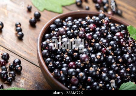 Reife schwarze Johannisbeeren in einem Ton Platte auf einem braunen Holz- Hintergrund. Platz für Text Stockfoto