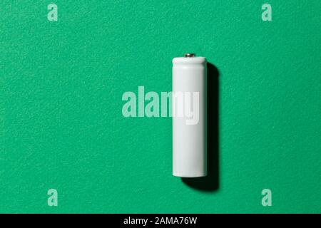 Weiße AA-Batterien auf grünem Hintergrund, Draufsicht. Leerzeichen für Text Stockfoto