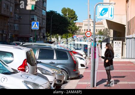 Murcia, Spanien, 11. Januar 2020: Frau, die mit einem Ticketautomaten bezahlt, um ihr Auto zu parken. Stockfoto