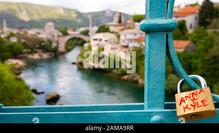 Anna und Kyle lieben ein Vorhängeschloss, das von der Hafenbrücke (Lucki Most) über den Fluss Neretva mit Blick auf die Alte Brücke in Mostar, Bosnien und Herzeg hängt Stockfoto