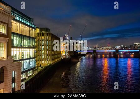 Blick nach Westen von der London Bridge entlang der Themse in Richtung Cannon Street Railway Bridge bei Nacht mit beleuchteten Büros auf der South Bank, Großbritannien Stockfoto