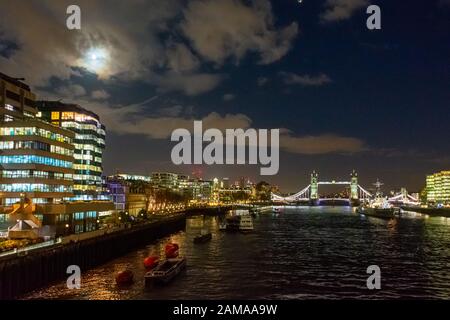 Blick nach Osten von der London Bridge entlang der Themse in Richtung Tower Bridge nachts mit dem Mond über London Stockfoto