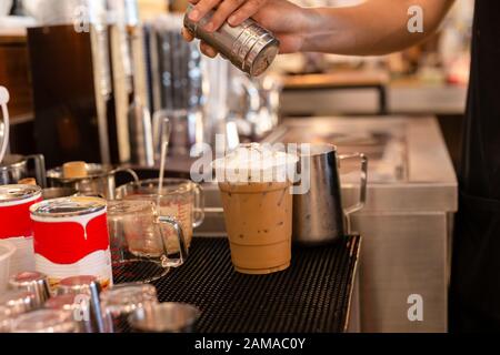 Barista streut Kakaopulver in Café auf Eisschokolade. Stockfoto