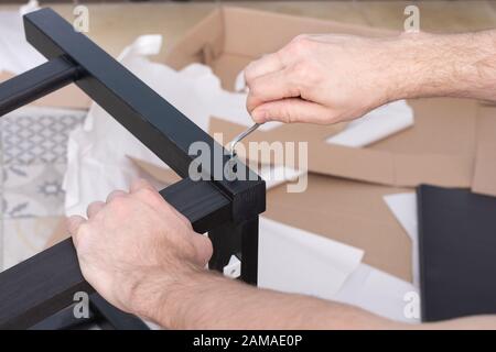 Montage von Holzmöbel des Essstuhls. Nahaufnahme des Tischlers mit einem Innensechskantschlüssel. Stockfoto