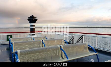 Leeres Panoramadeck der Fähre auf dem Waddenzee mit der Kirche von Holwerd in der Ferne. Stockfoto