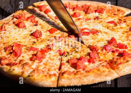 Nahaufnahme selektive Messerscheiben frische leckere Pizza Margherita mit Käse und Tomaten auf der Oberseite Stockfoto