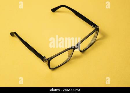Schwarze Brille mit klaren Linsen. Brillenrahmen auf gelbem Hintergrund. Brille zur Korrektur menschlicher Visionen oder zur Arbeit an einem Computer. Augenschutz Stockfoto