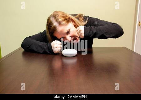 Person, die auf ihrem google Home Mini schreit und wütend ist, weil es nicht zuhört Stockfoto