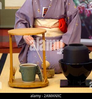 Japanische Teezeremonie Chanoyu. Frau in traditionellem Kimono pors heißes Wasser mit Chashaku in die Teeschale gekleidet. Stockfoto