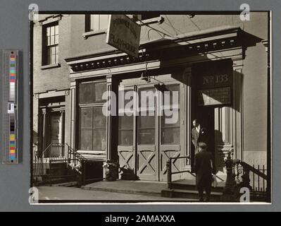 Provincetown Playhouse, 133 MacDougal Street, Manhattan Code: III.D.1. Schwarzer Mann steht in der Tür des Theaters, (ehemaliger stabiler) weißer Mann unten in den Stufen, beide blicken nach links vom Rahmen, Zeichen werfen Schatten. Citation/Reference: CNY# 192; Provincetown Playhouse, 133 MacDougal Street, Manhattan. Stockfoto