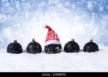 Blauer Weihnachtshintergrund - Dekorierte schwarze Kugeln mit Santa hat On Snow mit Schneeflocken und Sternen. Stockfoto