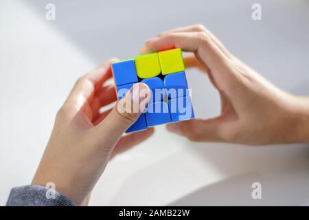 Perm, Russland, 28. September 2019: Rubik Würfel in den Händen eines Jungen. Das Kind hält einen Rubik-Würfel auf einem hellen Hintergrund und spielt damit. Nahaufnahme. Stockfoto