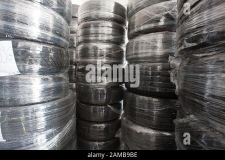 Stapel gebrauchte Reifen, die mit Folie umhüllt sind, sind auf Lager. Schwarzer Gummireifen, Teil des Fahrzeugs, Ersatzteil. Stockfoto