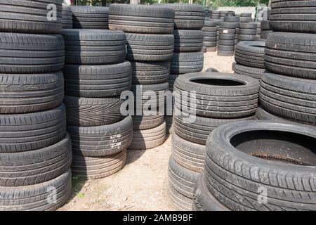 Auf dem Platz liegen die Pfähle der gebrauchten Reifen. Schwarzer Gummireifen, Teil des Fahrzeugs, Ersatzteil. Stockfoto