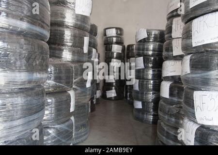 Stapel gebrauchte Reifen, die mit Folie umhüllt sind, sind auf Lager. Schwarzer Gummireifen, Teil des Fahrzeugs, Ersatzteil. Stockfoto