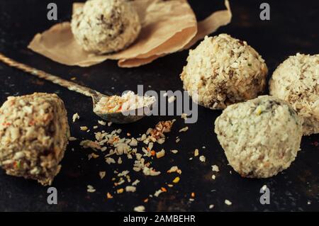 Gesunde Schokoladenenergiebisse mit Nüssen, Datteln, Kokosflocken auf einem Holztisch. Hausgemachte vegetarische, glutenfreie, gesunde Snacks. Stockfoto