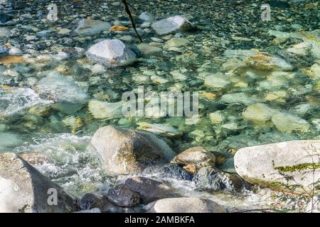Klares Wasser fließt über Felsen im Denny Creek im Staat Washington. Stockfoto