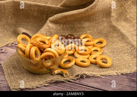 Kleine Bagels und Pralinen auf dem Hintergrund rauer Homespun-Qualität Stockfoto