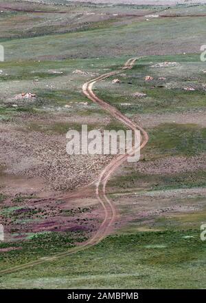 Draufsicht auf eine kurvenreiche Straße zwischen grünen Hügeln. Republik Altai, Russland Stockfoto