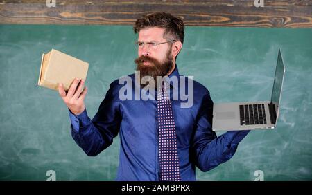 Lehrer bärtigen Hipster hält Buch und Laptop. Mit der rechten Lehre Methode wählen. Lehrer mit modernen pädagogischen Ansatz. Moderne Technologien profitieren. Moderne statt überholt. Digitale gegen Papier. Stockfoto