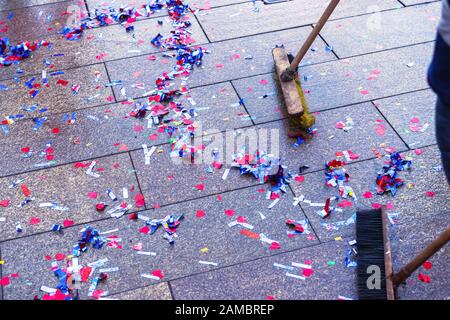 Mehrfarbige Glitzerscheiben auf dem Straßenbelag nach dem Urlaub saubere Wischtücher. Die Arbeit des Müllsammlers. Stockfoto