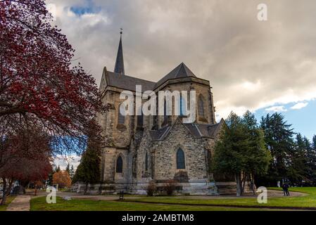 BARILOCHE, ARGENTINIEN, 18. JUNI 2019: Farbenfroher Pfad mit roten Bäumen neben der Kathedrale Nuestra Senora del Nahuel Huapi. Stockfoto