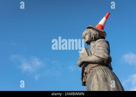 Ich schaue auf die Statue von Jean Armour in Dumfries, Schottland, mit einem Verkehrskegel auf dem Kopf an einem hellen, sonnigen Tag. Stockfoto