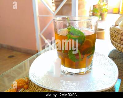 Frischer Minztee in einem Glas in einem Restaurant in Marrakesch, Marokko. Es handelt sich um einen typischen Berbertee, der auch Berber-Whisky genannt wird. Stockfoto