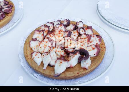 Eine obenliegende Foto von Pulpo a la Gallega, eine Krake mit gekochten Kartoffeln, typische spanische galizische Gericht, auf einer traditionellen hölzernen Platte eine Krickente backg Stockfoto