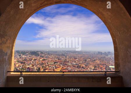 Panoramablick auf die Stadt Neapel durch den Bogen der mittelalterlichen Festung Castel Sant'Elmo. Skyline mit der historischen Altstadt, Spaccanapoli Straße. Stockfoto