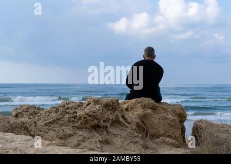 Ein einsamer Mann, der dem Meer zugewandt ist Stockfoto
