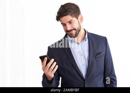 Schuss eines jungen Geschäftsmannes, der sein Handy in der Hand hält, und Textnachrichten, während er auf einem isolierten weißen Hintergrund steht. Stockfoto