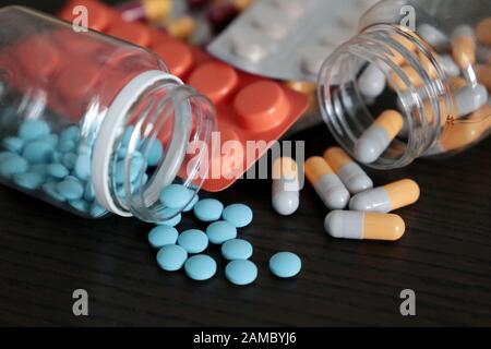 Pillen und Kapseln auf dunklen Holztisch, viele bunte Medikation close-up. Konzept der Apotheke, Vitamine, Gesundheit Stockfoto