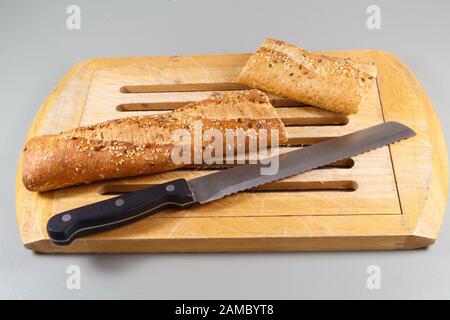 Zwei Stücke französisches Baguette-Brot und Messer auf einem Holzhackbrett Stockfoto