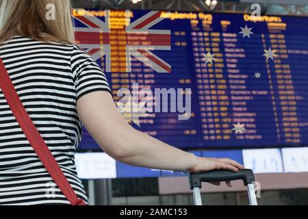 Frau schaut auf die Anzeigetafel am Flughafen. Wählen Sie ein Land Australien für Reise oder Migration aus. Stockfoto