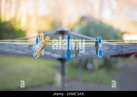 Gelbe, blaue und graue Kleidung pinkelt auf gelber Drehwaschlinie vor unscharfem grün/gelbem Hintergrund. Konzeptbild. Stockfoto