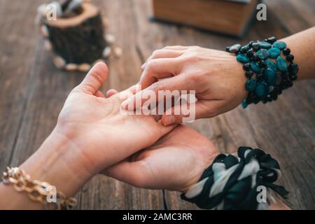 Nahaufnahme der Wahrsagerin zeigen Sie mit dem Finger auf die Palmenlinie der Frau und lesen Sie ihr Vermögen. Palmistry cpncept Stockfoto