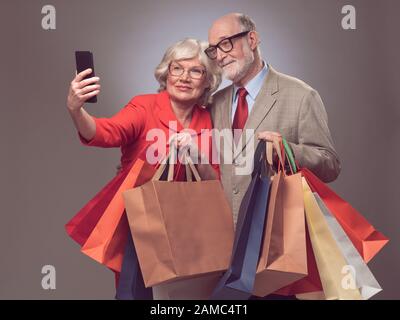 Älteres Paar mit vielen Papier-Einkaufstaschen, die selfie einnehmen Stockfoto