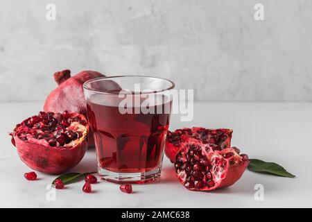 Glas Granatapfelsaft mit frischen Granatapfeln auf Marmortisch. Konzept für gesunde Getränke Stockfoto