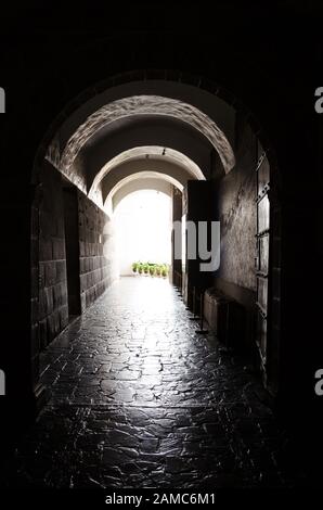 Öffnen Sie die Tür am Ende des Steinkorridors in Cusco, Peru. Licht strömt durch ihn und lädt zum sonnigen Innenhof ein Stockfoto