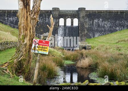 "Kein Schwimmen" und "tiefes Wasser" Schild vor einer Steinstaumauer des Fisher Reservoirs, Cumbria, Großbritannien Stockfoto