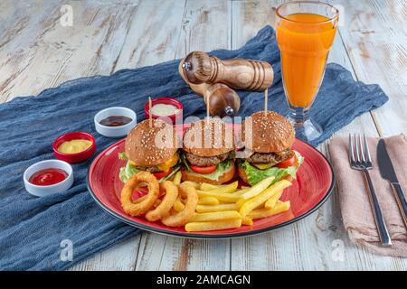 Drei Mini-Hamburger. Hausgemachte köstliche drei Mini-Burger mit Salat, Sauce und Zwiebelringen und pommes frites. Hausgemachte Mini-Burger-Schieberegler. Stockfoto